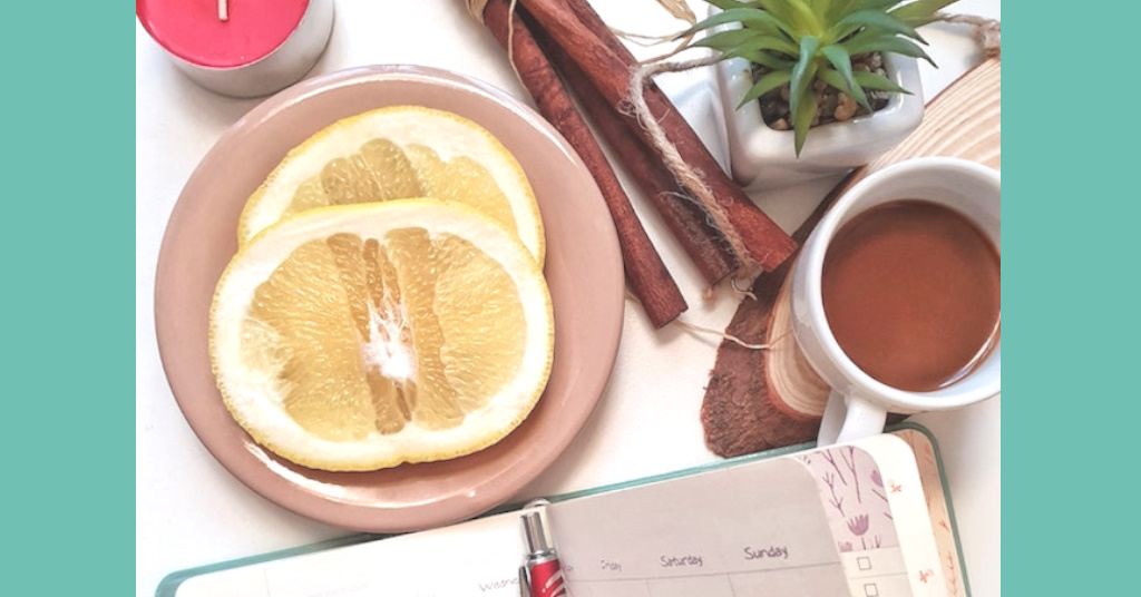 Morning routine of journal, warm drink,, lemon slices, and candle.