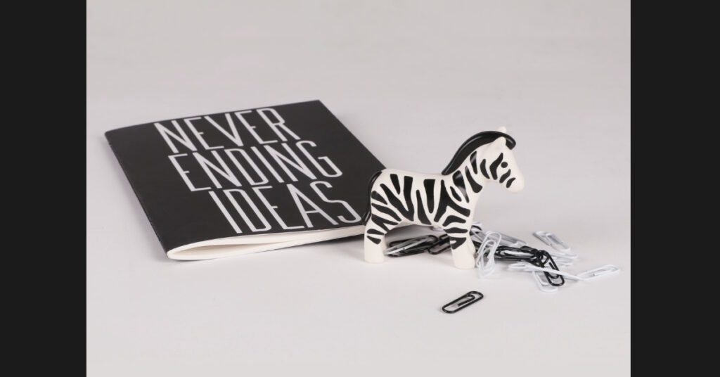 Notebook, zebra figurine, paper clips in black and white.